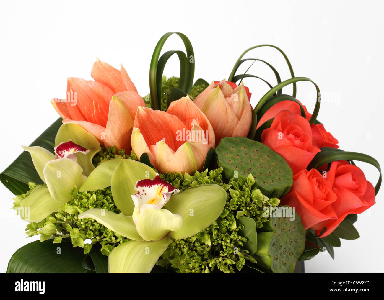 Un gros plan d'un bouquet de fleurs colorées. Roses orange, vert graines lily pads, des tulipes roses, orchidées cymbidiums Banque D'Images