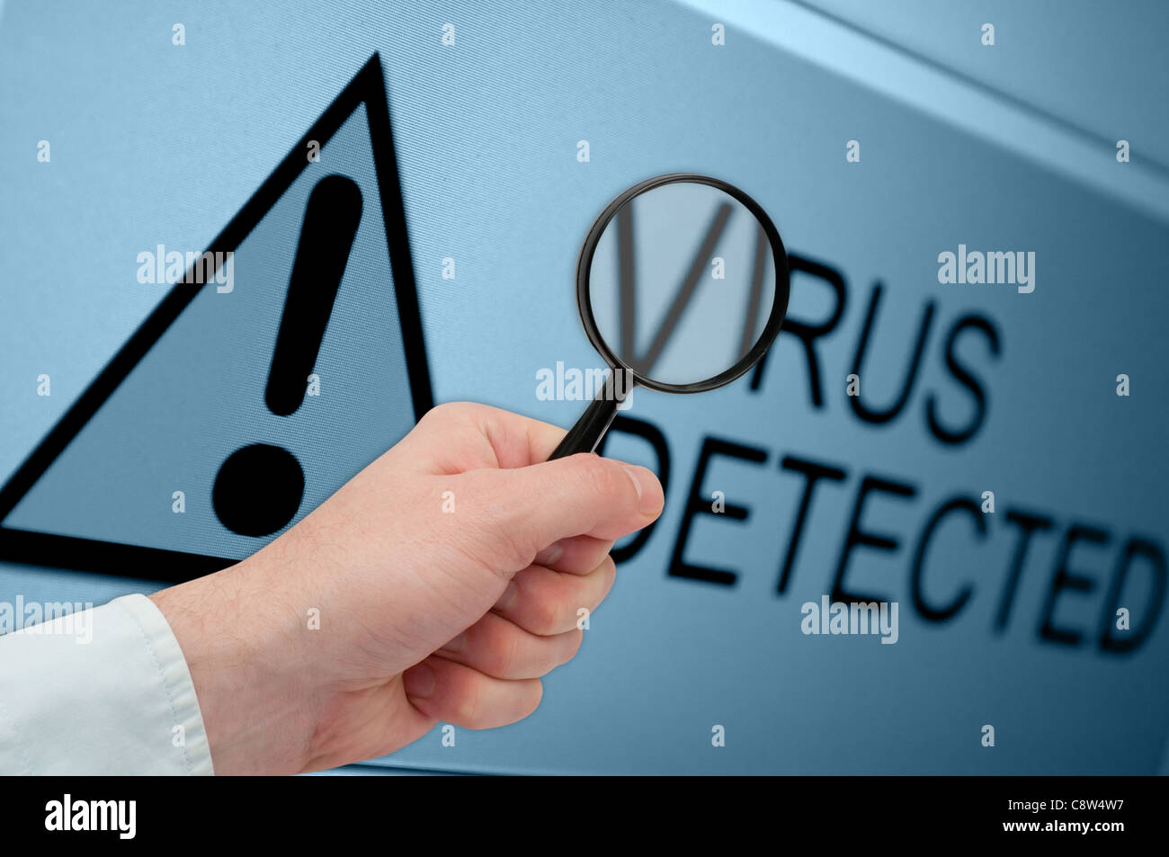 Man's Hand Holding Loupe sur Virus détecté signer sur le moniteur Banque D'Images