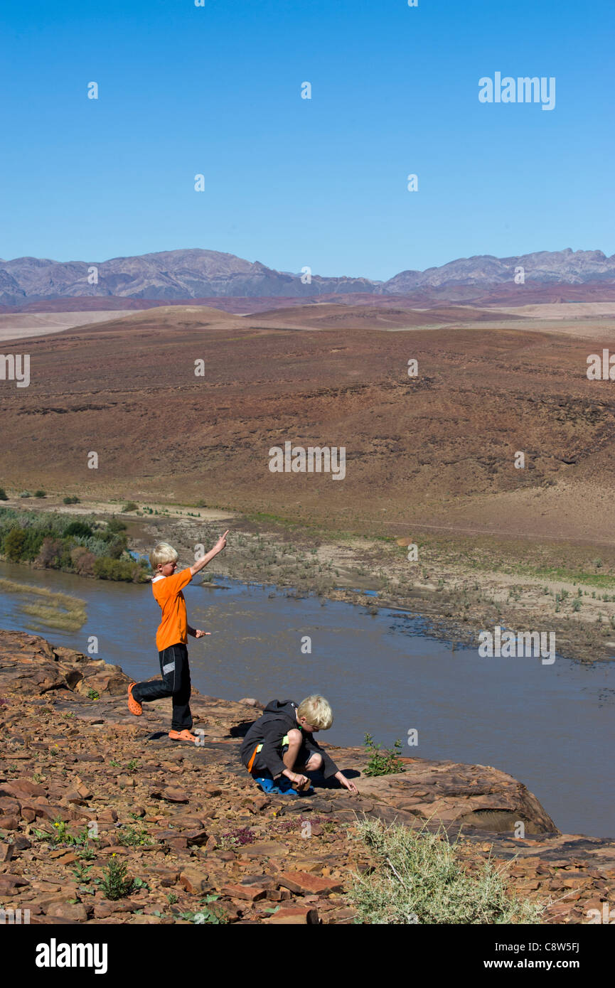 Les garçons de jeter des pierres à partir d'un point de vue dans l'Oranje vue sur la rivière de l'ouest de la Namibie Aussenkehr Banque D'Images