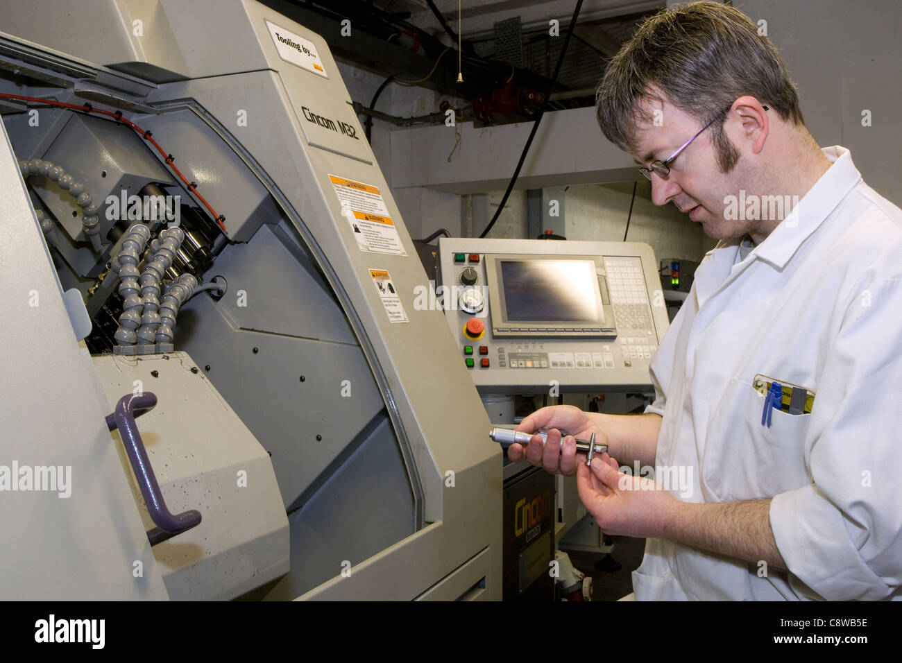 Tour CNC operator contrôler l'exactitude d'un travail avec un micromètre Banque D'Images