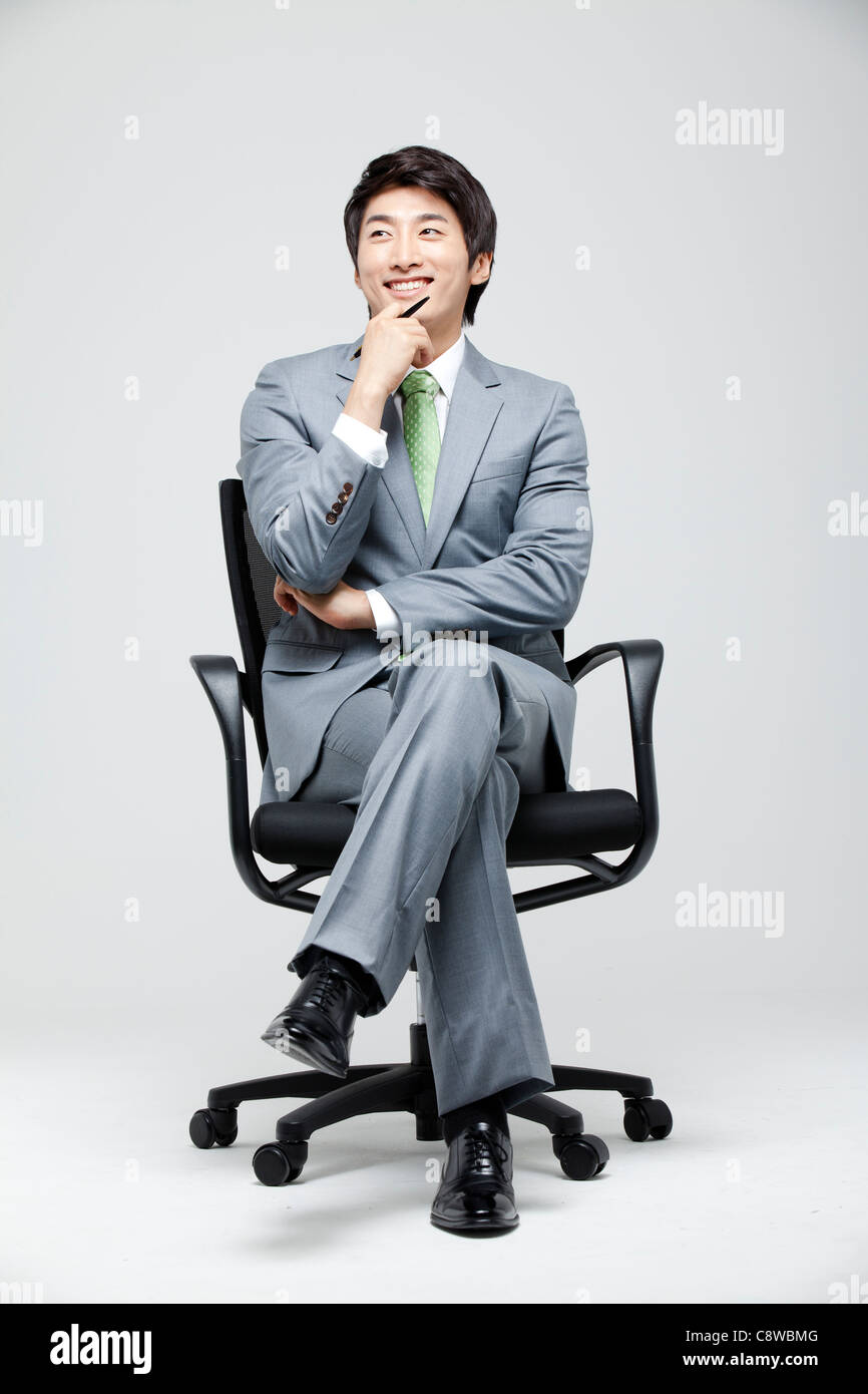 Asian Businessman Holding Pen in Hand On Chin Banque D'Images