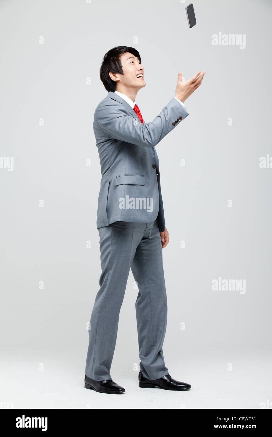 Asian Businessman Throwing Cell Phone dans l'air Banque D'Images