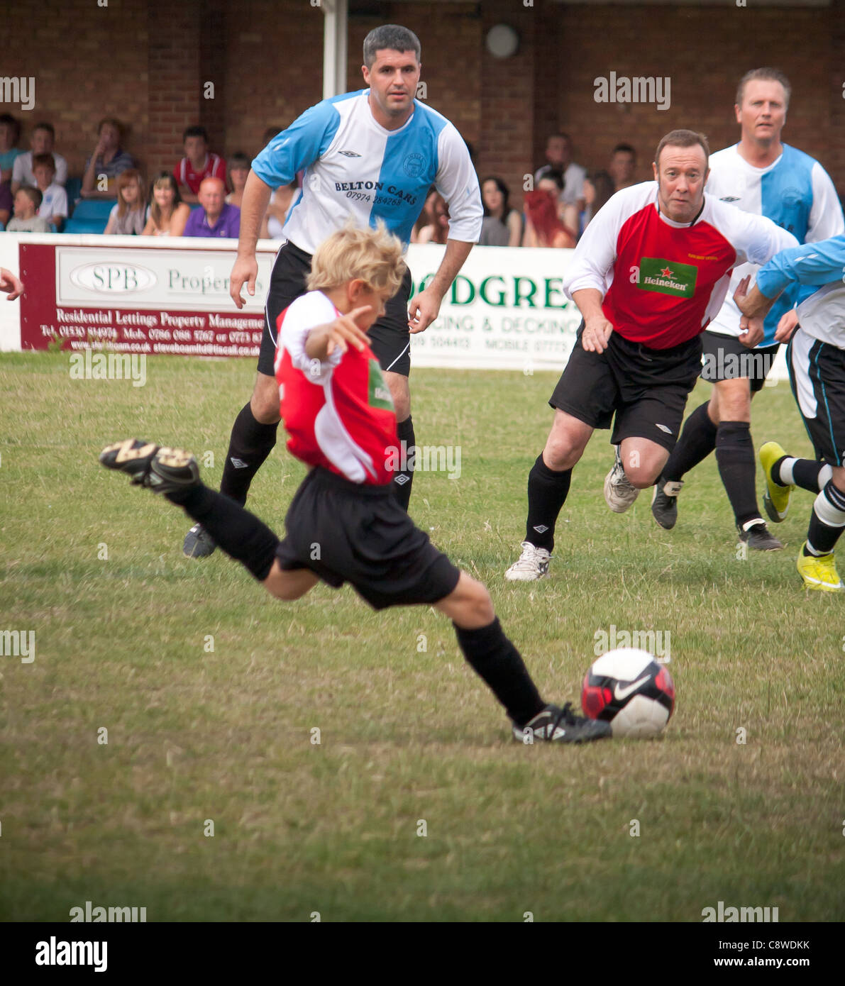 Un match de football de l'équipe sportive locale montrant des hommes et des  femmes de tous âges et de toutes tailles à jouer au football pour le  plaisir et le divertissement Photo