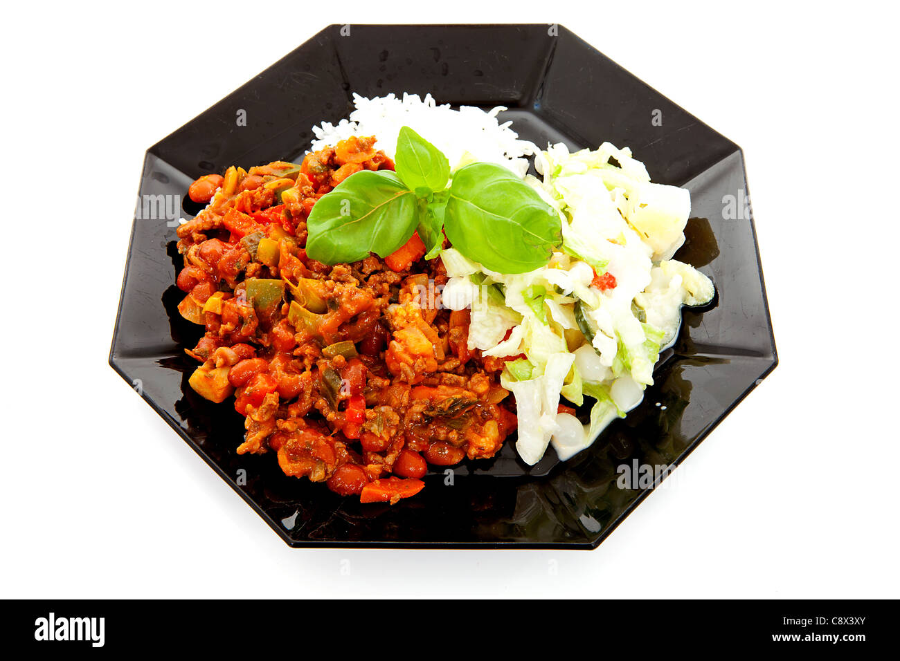 Plaque avec de délicieux chili con carne, riz et salade verte sur fond blanc Banque D'Images
