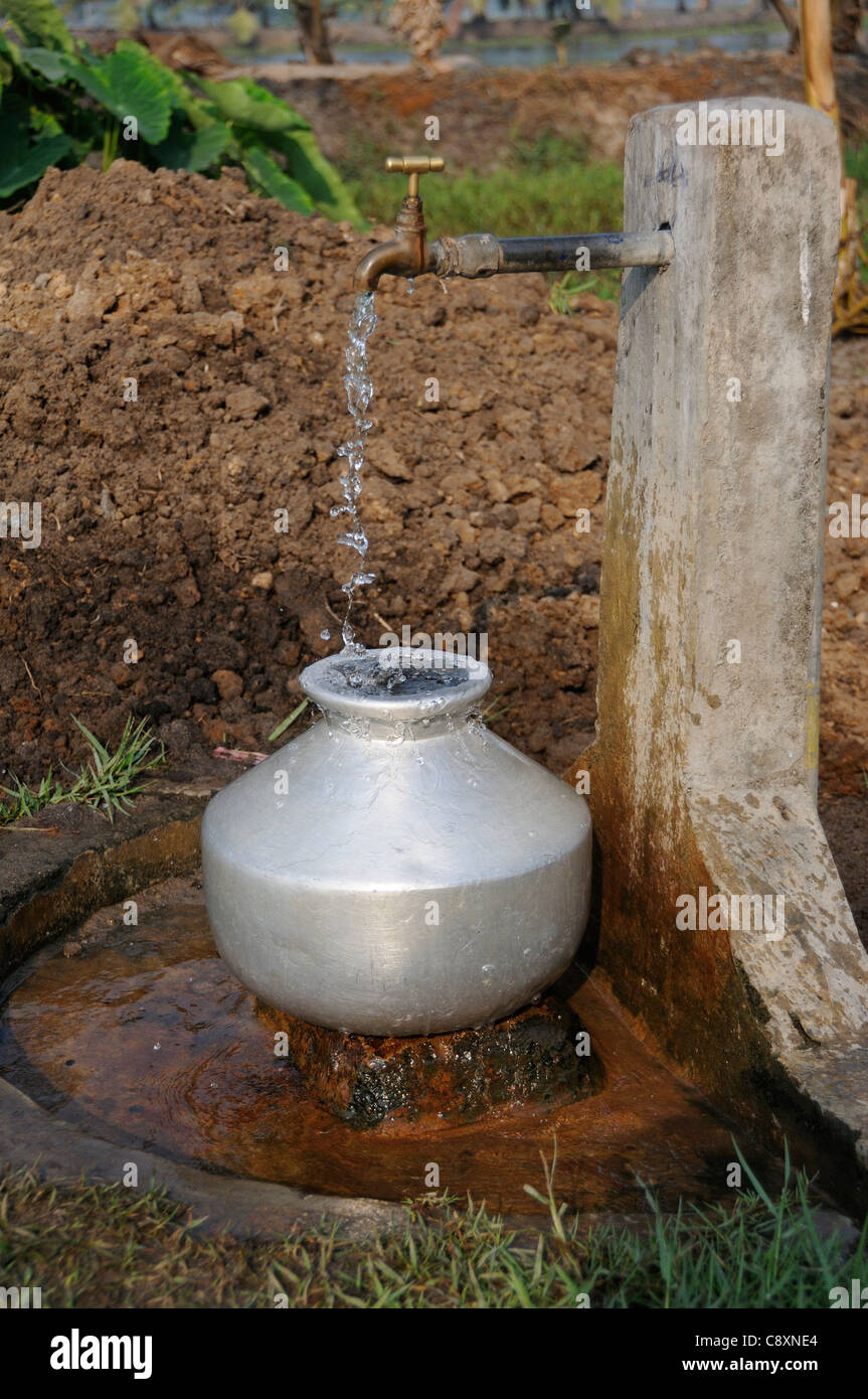 En cascade de l'eau potable à partir de la borne fontaine et tomber dans une casserole en aluminium sur une rive du fleuve sur les Backwaters du Kerala, Inde Banque D'Images