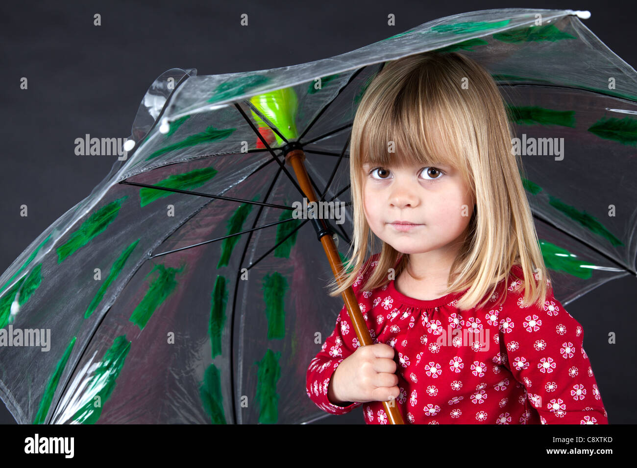 Petite fille rouge blanc à pois parapluie cavalier tête de canard sur fond noir s'amusant Banque D'Images