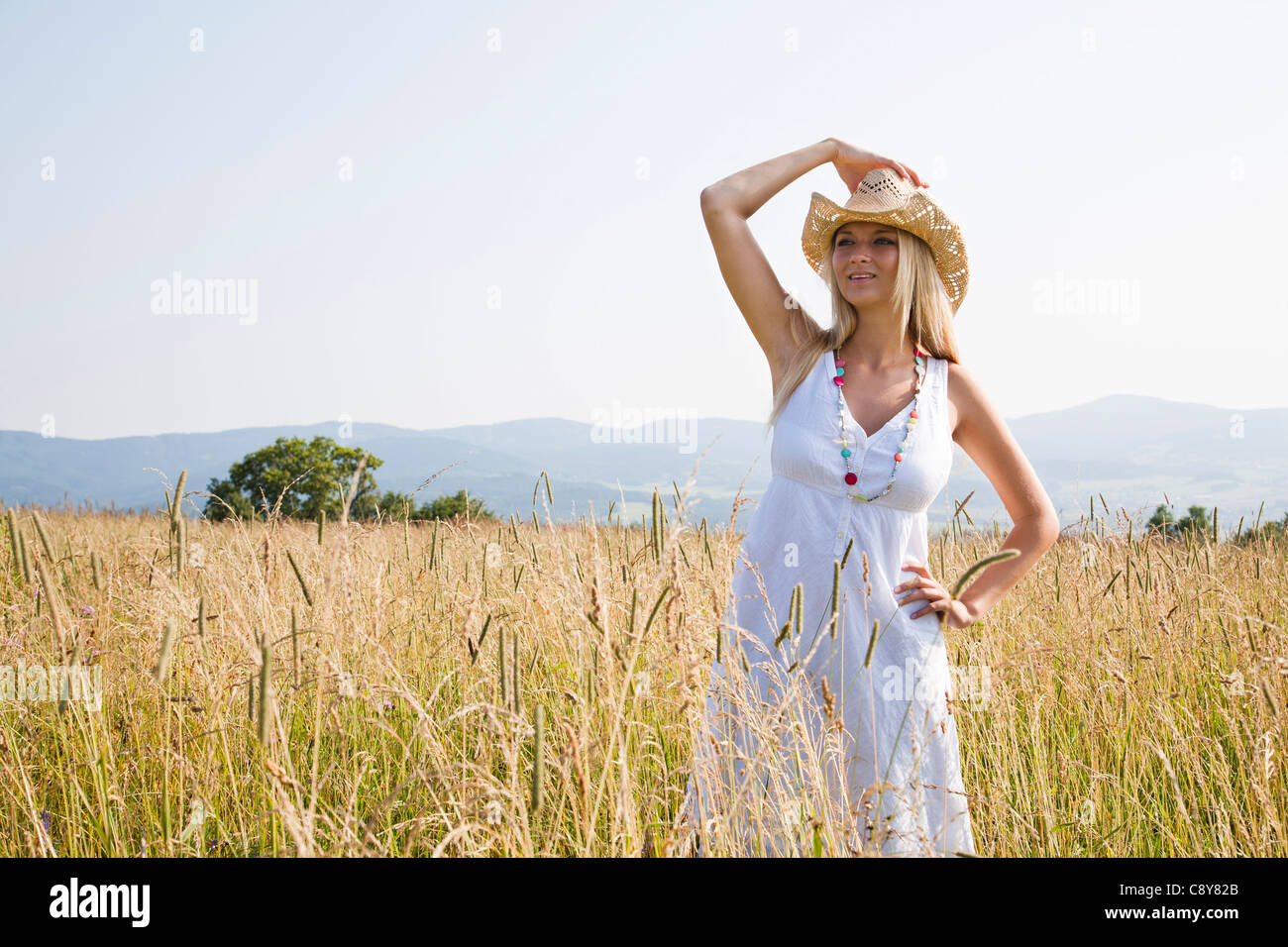 Young woman with hat standing in field Banque D'Images