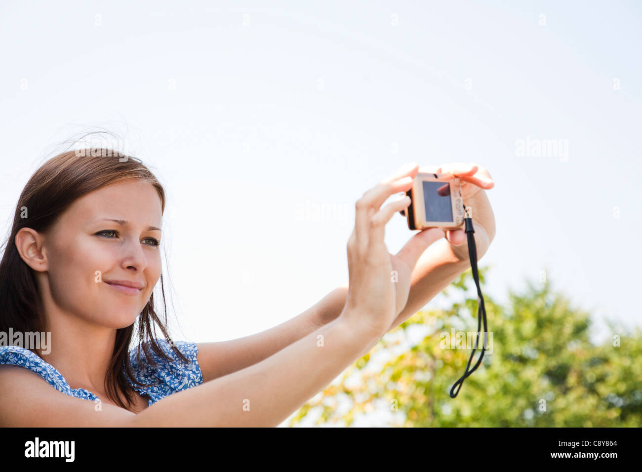 Young woman taking photo d'elle-même avec un appareil photo numérique Banque D'Images