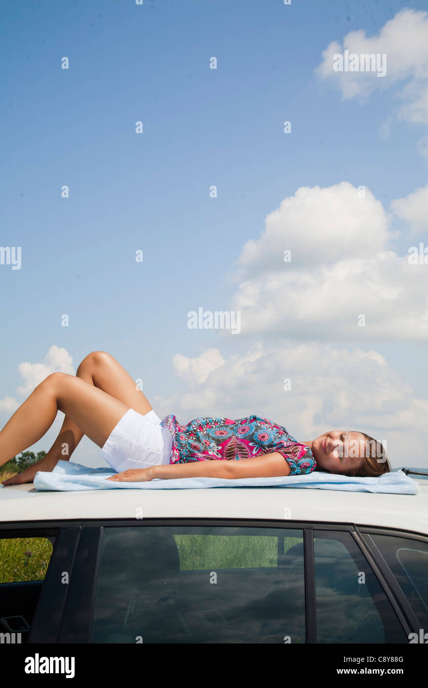 Jeune femme endormie sur toit de voiture Banque D'Images