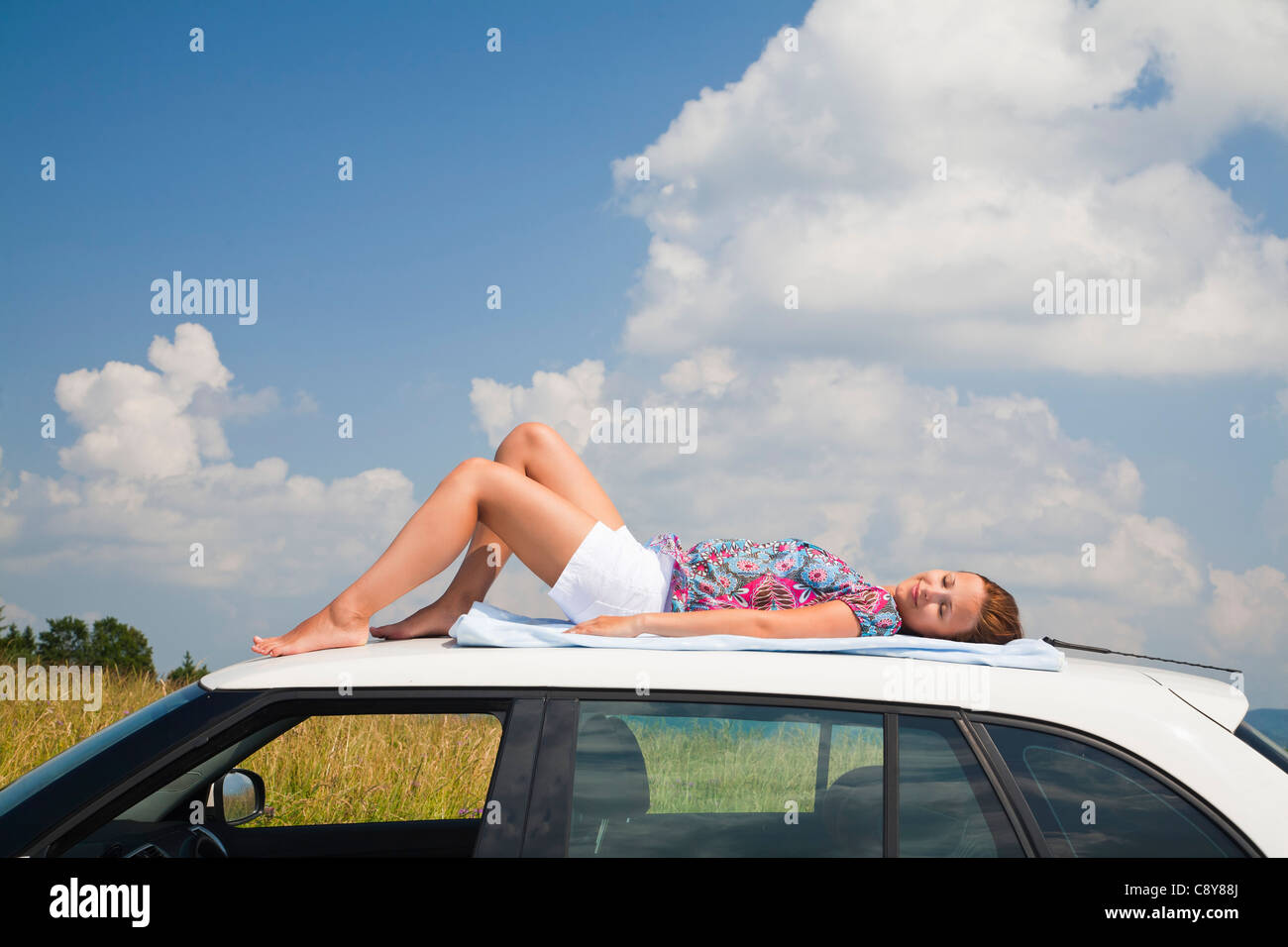 Jeune femme endormie sur toit de voiture Banque D'Images