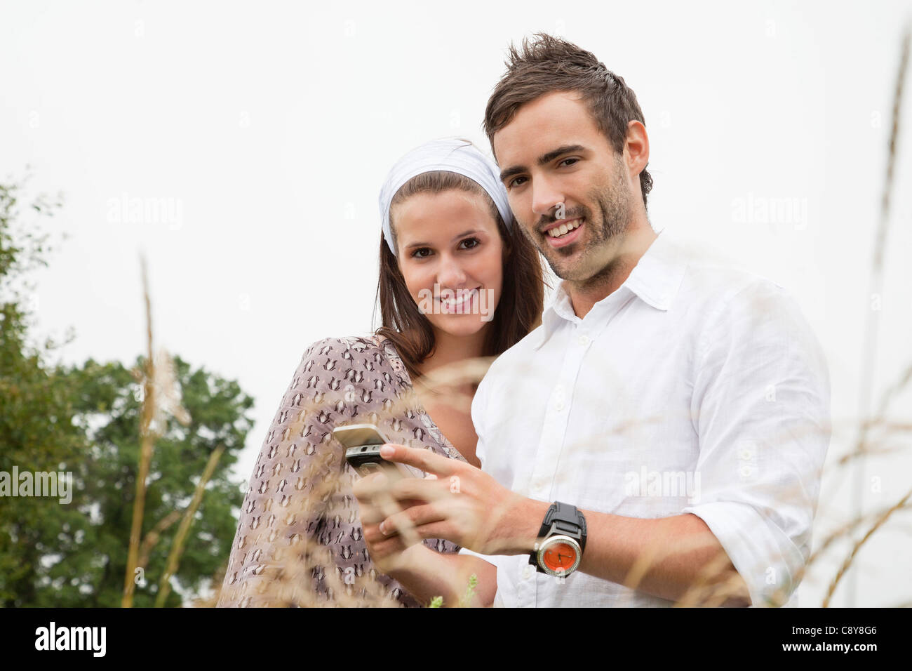 Portrait of young couple reading message on mobile phone Banque D'Images