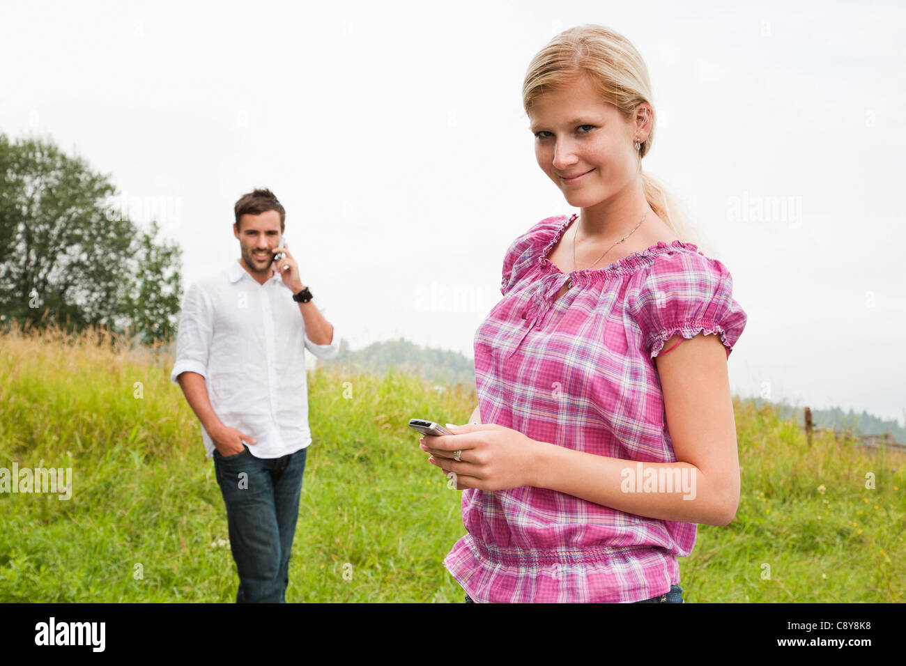 Portrait de jeune femme et l'homme avec les téléphones mobiles Banque D'Images