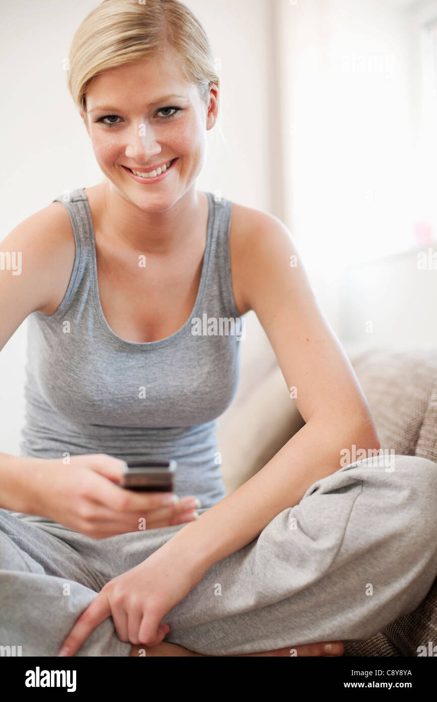 Portrait of young woman at home with mobile phone Banque D'Images