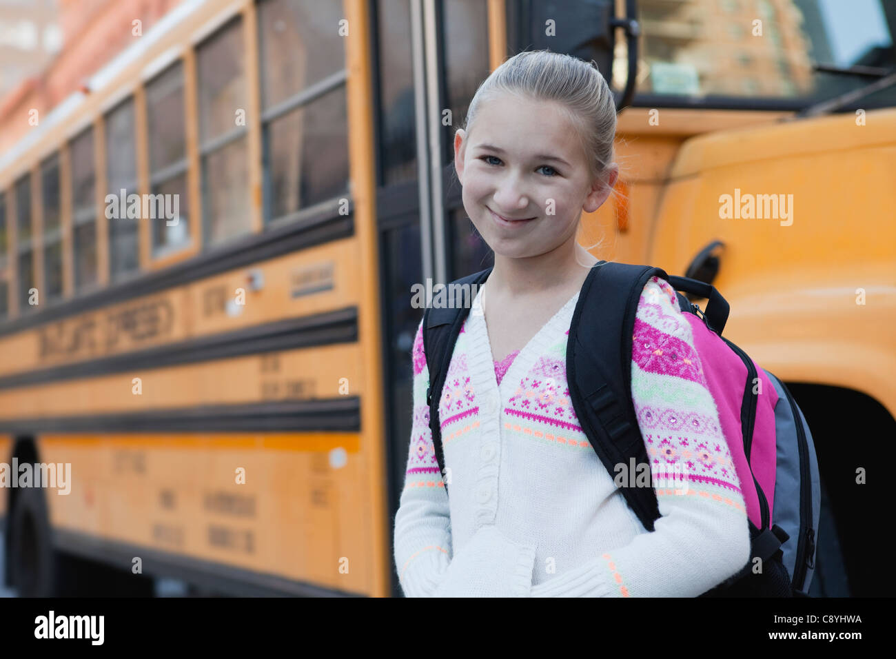 USA, New York State, New York, Portrait of smiling girl (10-11), d'autobus scolaires en arrière-plan Banque D'Images