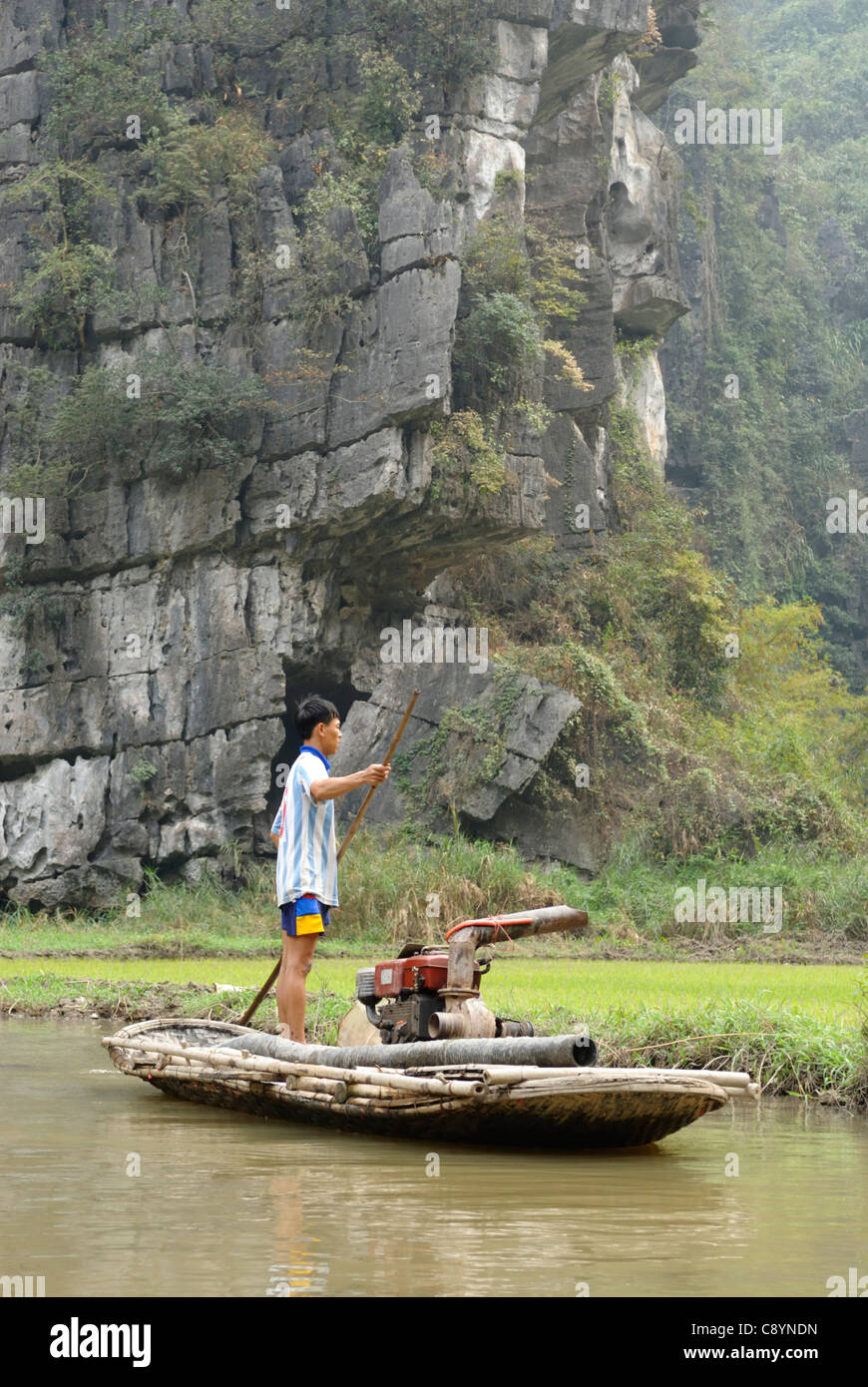 L'Asie, Vietnam, Tam Coc près de Ninh Binh. Dans le paysage aquatique de Tam Coc (trois grottes) jeune homme vietnamien de son travail... Banque D'Images