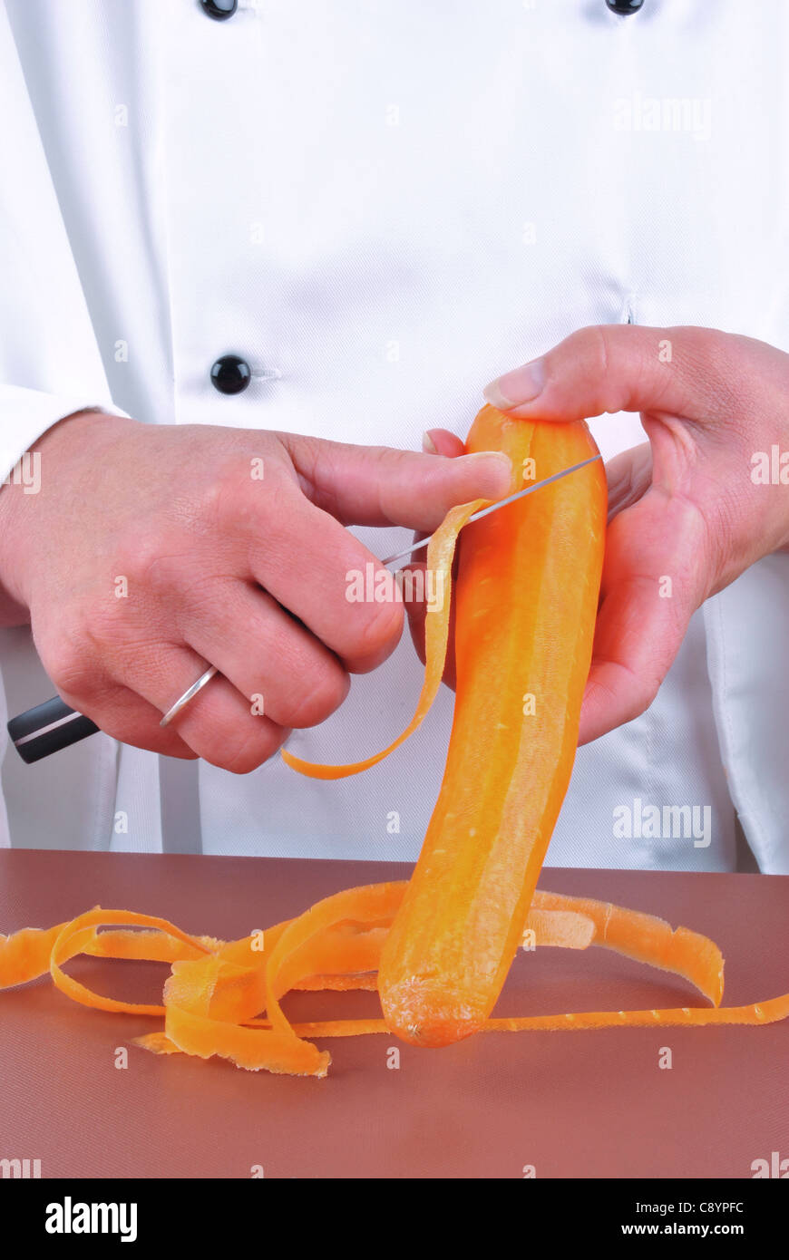 Femme chef coupe une carotte avec un couteau de cuisine Banque D'Images