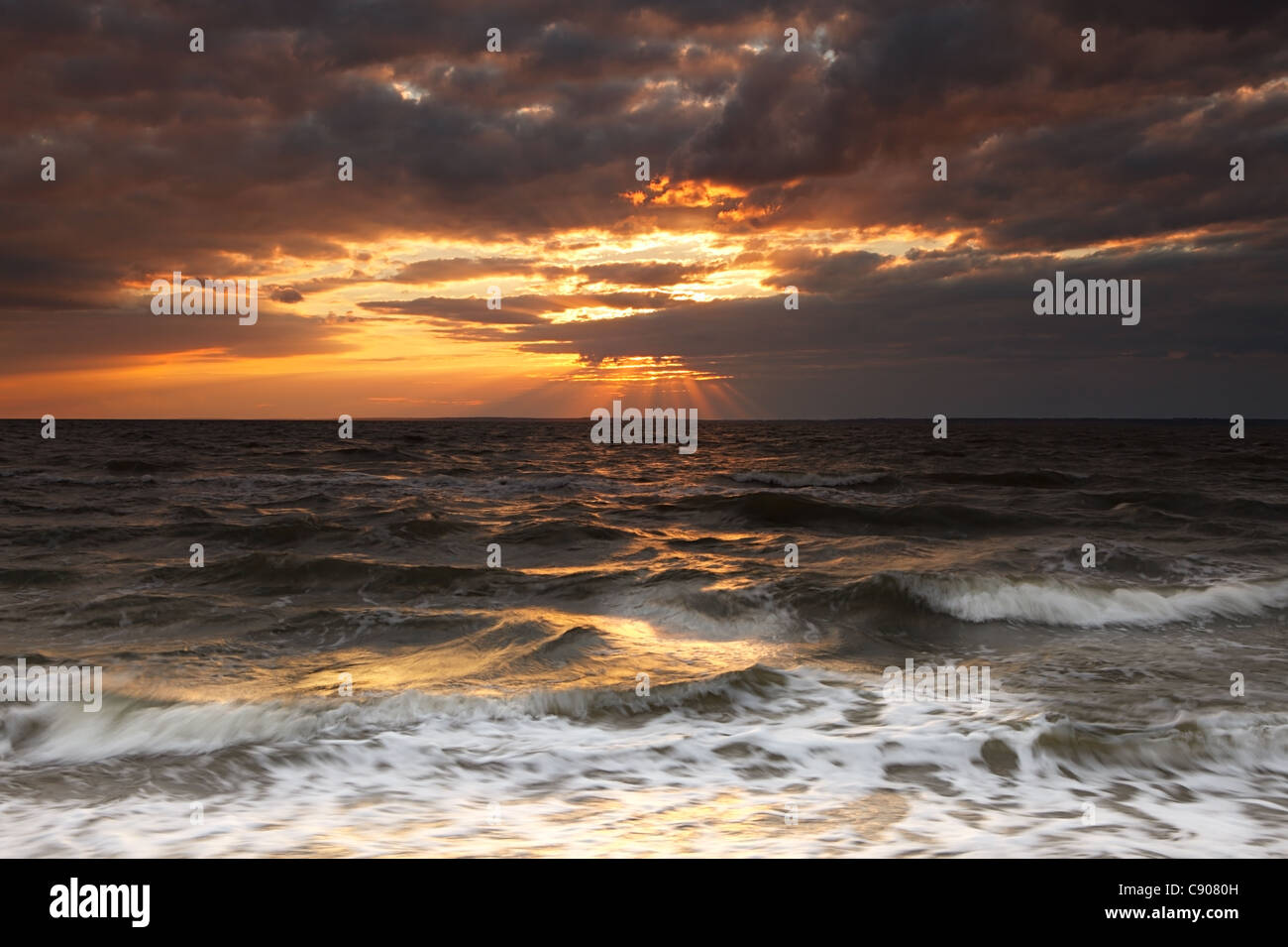 Nuageux coucher du soleil à la mer agitée Banque D'Images