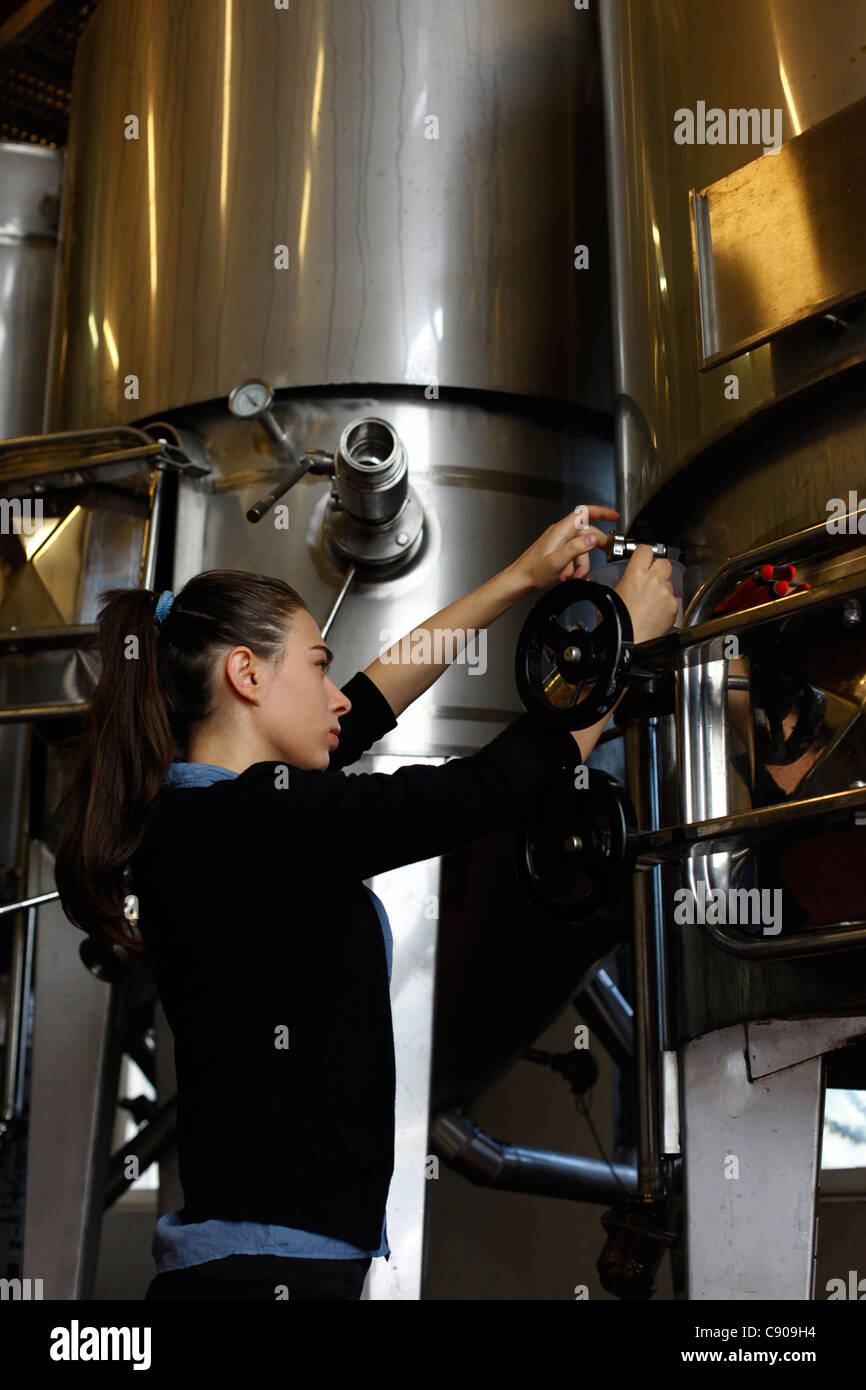 Un travailleur de verser le vin dans une cuve de fermentation en acier inoxydable à l'Amphora Winery près de Zichron Yaacov, au pied de la CARM Banque D'Images