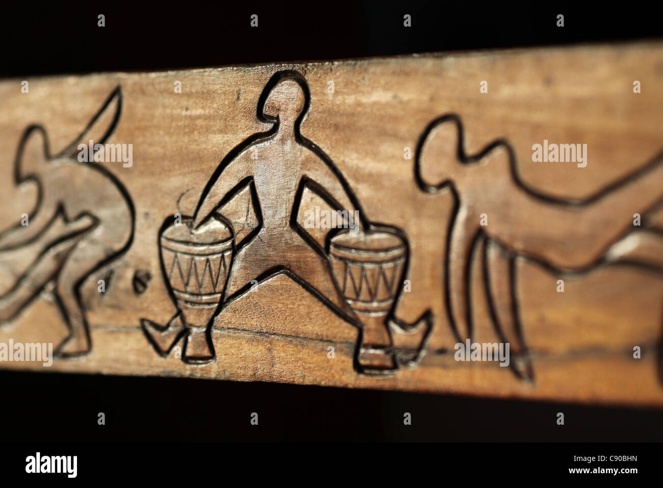 Sculpture sur bois traditionnelle malgache relief du détail description un batteur et quelques danseurs dans Be Hell-Ville, Nosy Be, Madagascar Banque D'Images