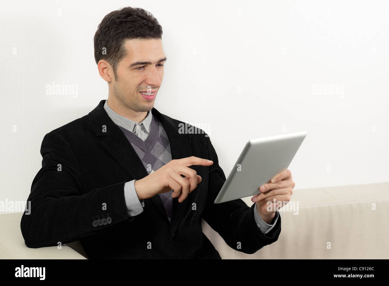 Businessman sitting on sofa et à l'aide d'un PC tablette numérique. Banque D'Images