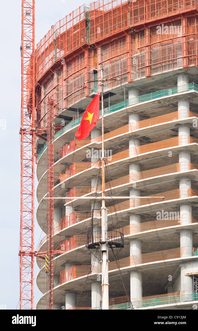 Bâtiment en construction au Vietnam avec le drapeau vietnamien au premier plan. Banque D'Images