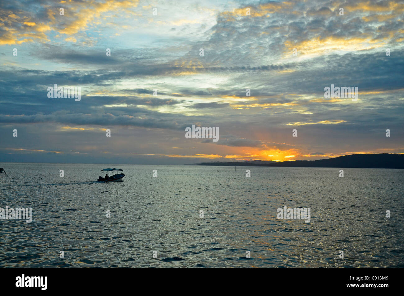 Petit bateau au coucher du soleil, Raja Ampat îles de Papouasie occidentale dans l'océan Pacifique, l'Indonésie. Banque D'Images
