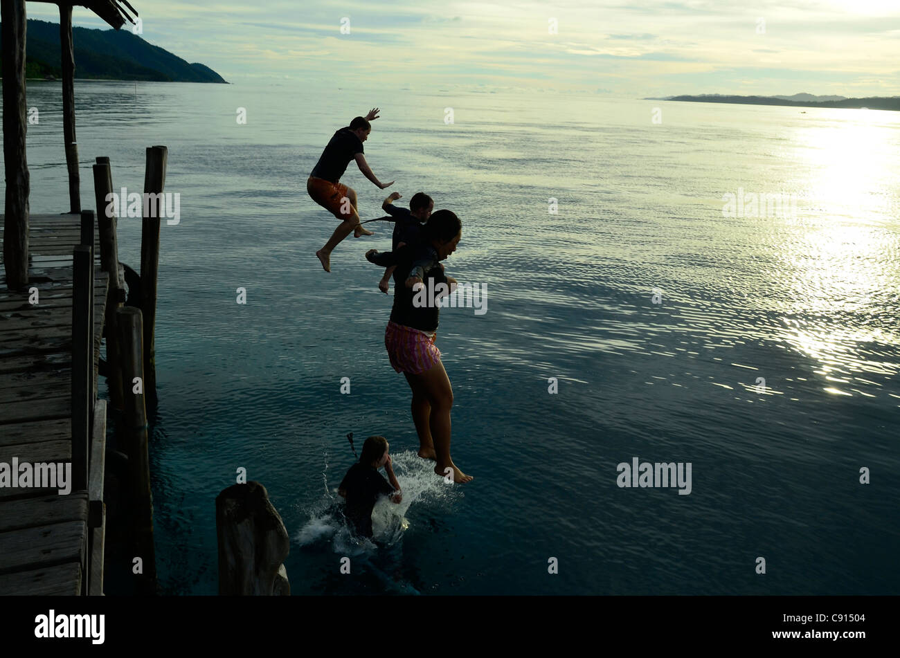 Les touristes de sauter une jetée à Kri Eco Resort Raja Ampat îles de Papouasie occidentale dans l'océan Pacifique, l'Indonésie. Banque D'Images