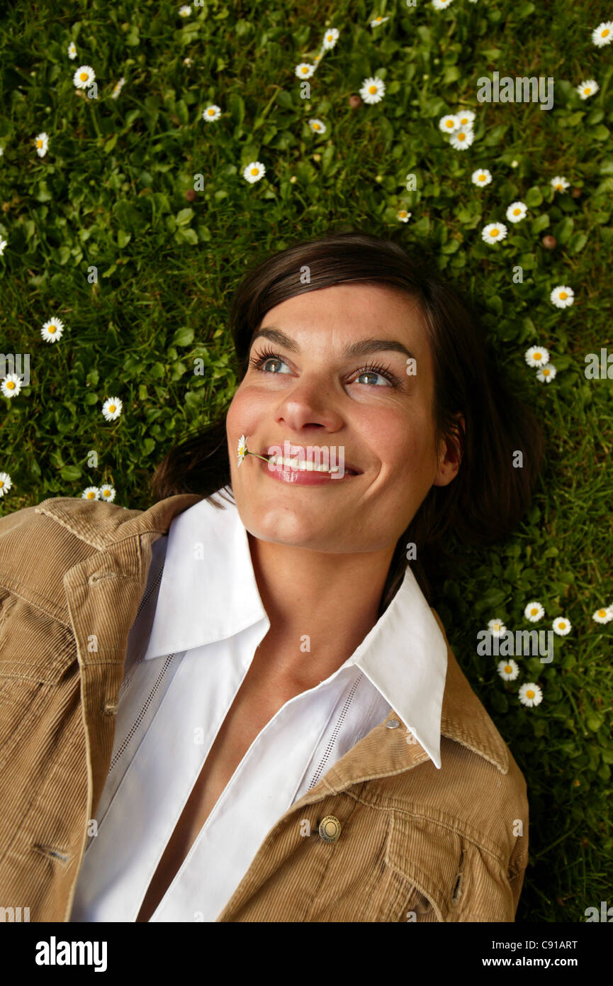 Mid adult woman lying in meadow daisy Banque D'Images