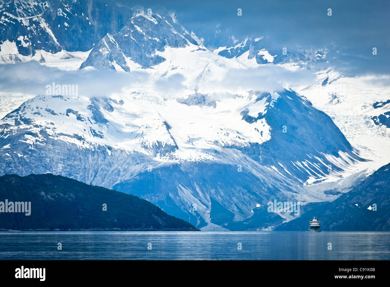 Un petit bateau de croisière naviguant à travers avec l'entrée d'Tarr Fairweather Range dans l'arrière-plan, Glacier Bay National Park , Alaska Banque D'Images