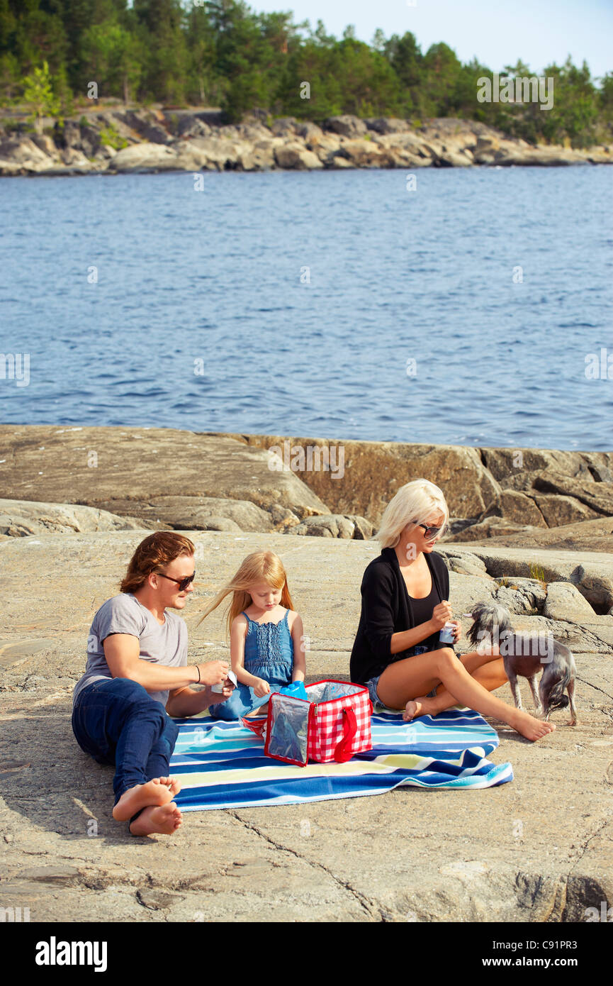 Family having picnic on rocks by lake Banque D'Images