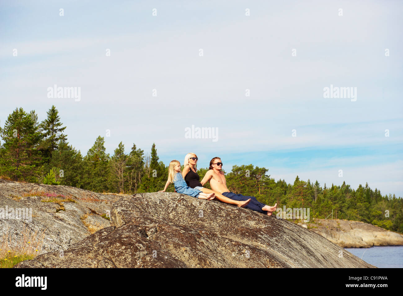 Family sitting on rock by lake Banque D'Images