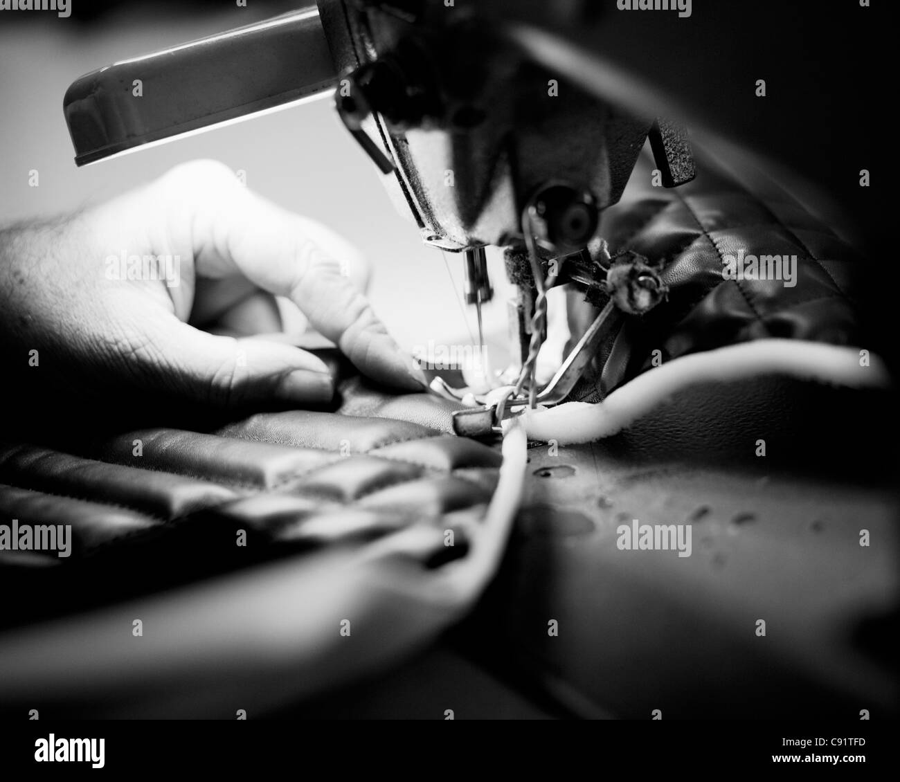 Un homme de suture un sac de luxe dans une usine de confection. Banque D'Images Un homme de suture un sac de luxe dans une usine de confection. Banque D'Images