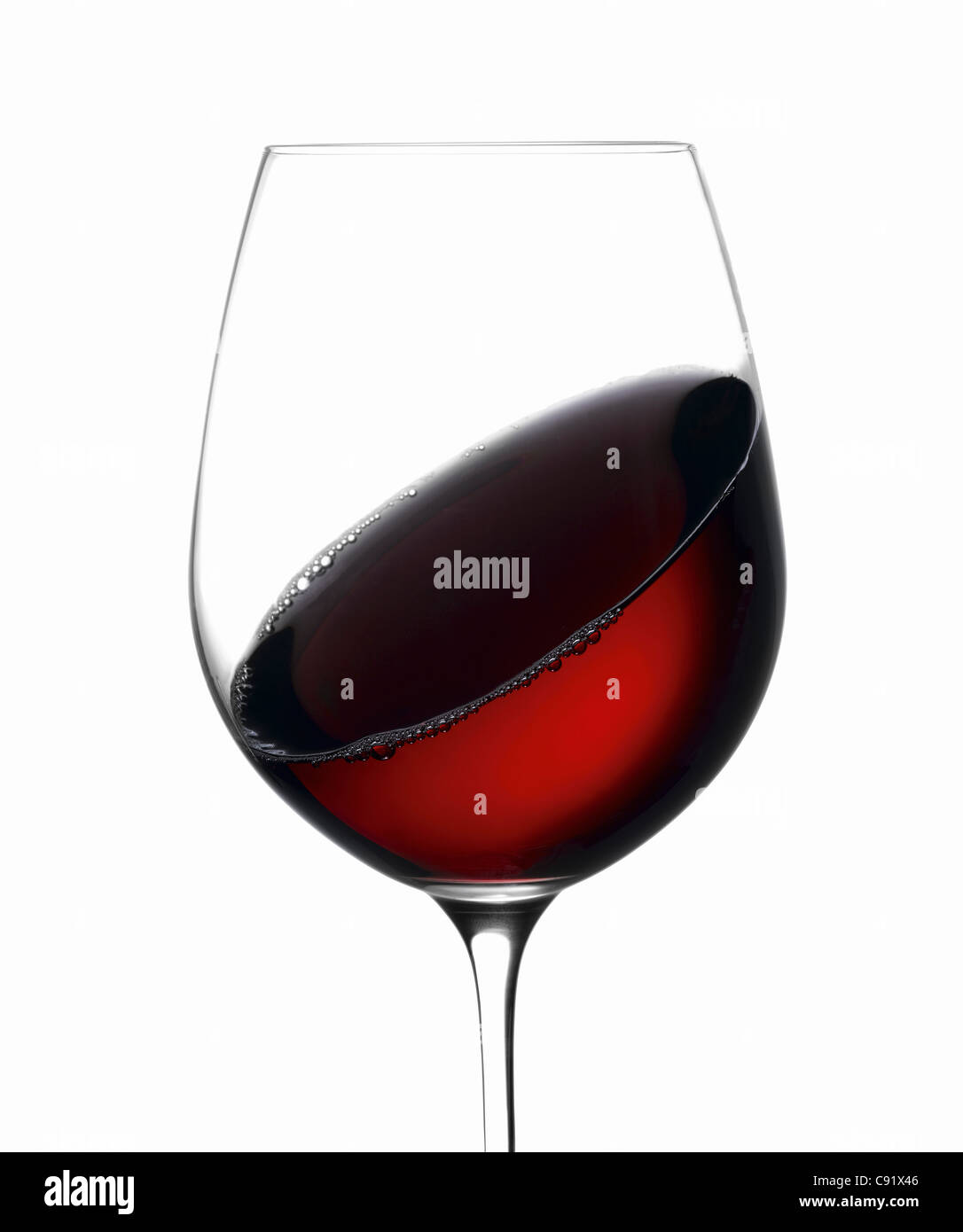 Verre de vin rouge sur fond blanc, verre tourbillonnant autour du vin Banque D'Images