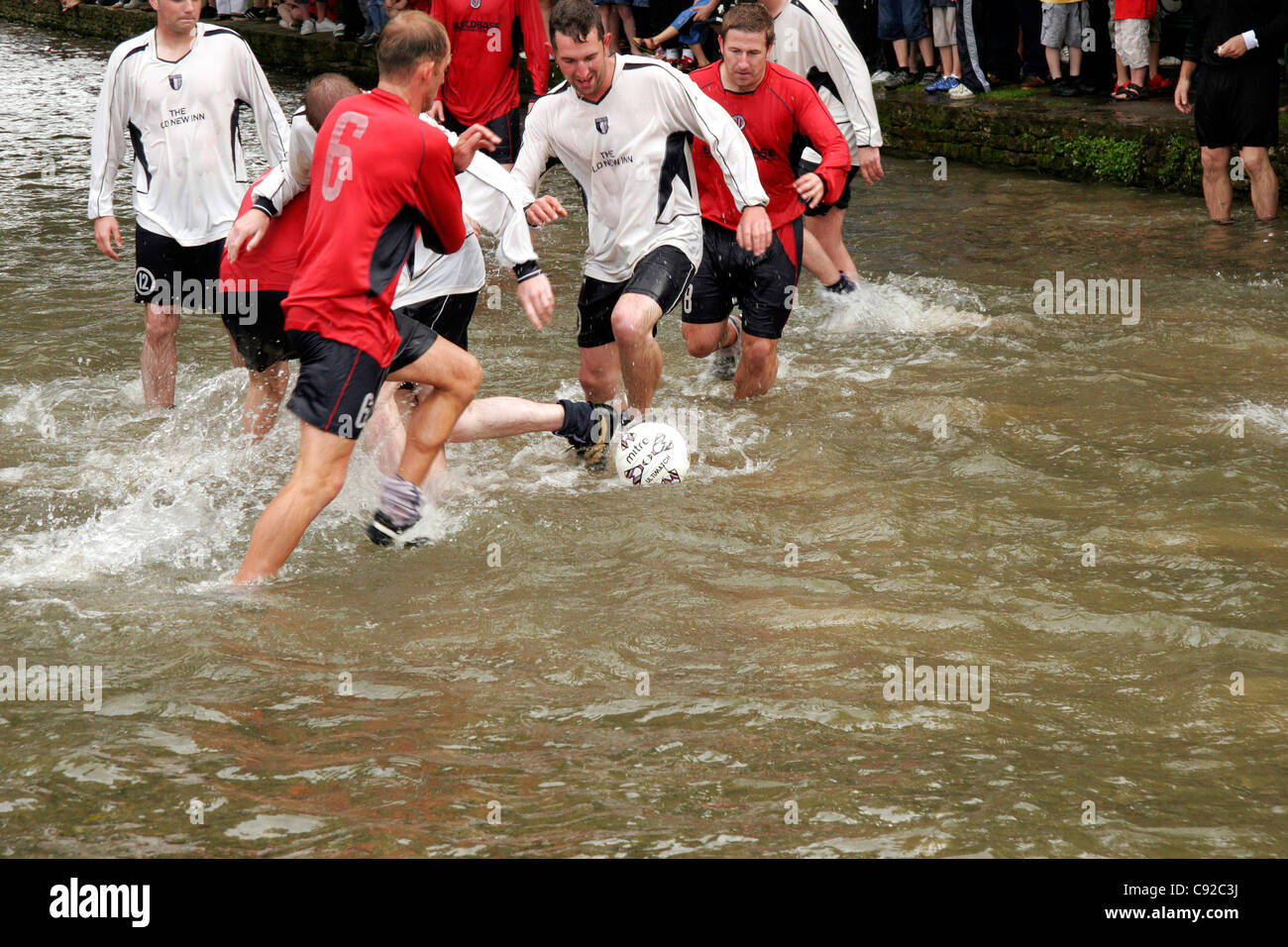 L'annuel original football dans la rivière, a lieu le lundi férié en Bourton-on-the-water, Gloucestershire, Angleterre Banque D'Images