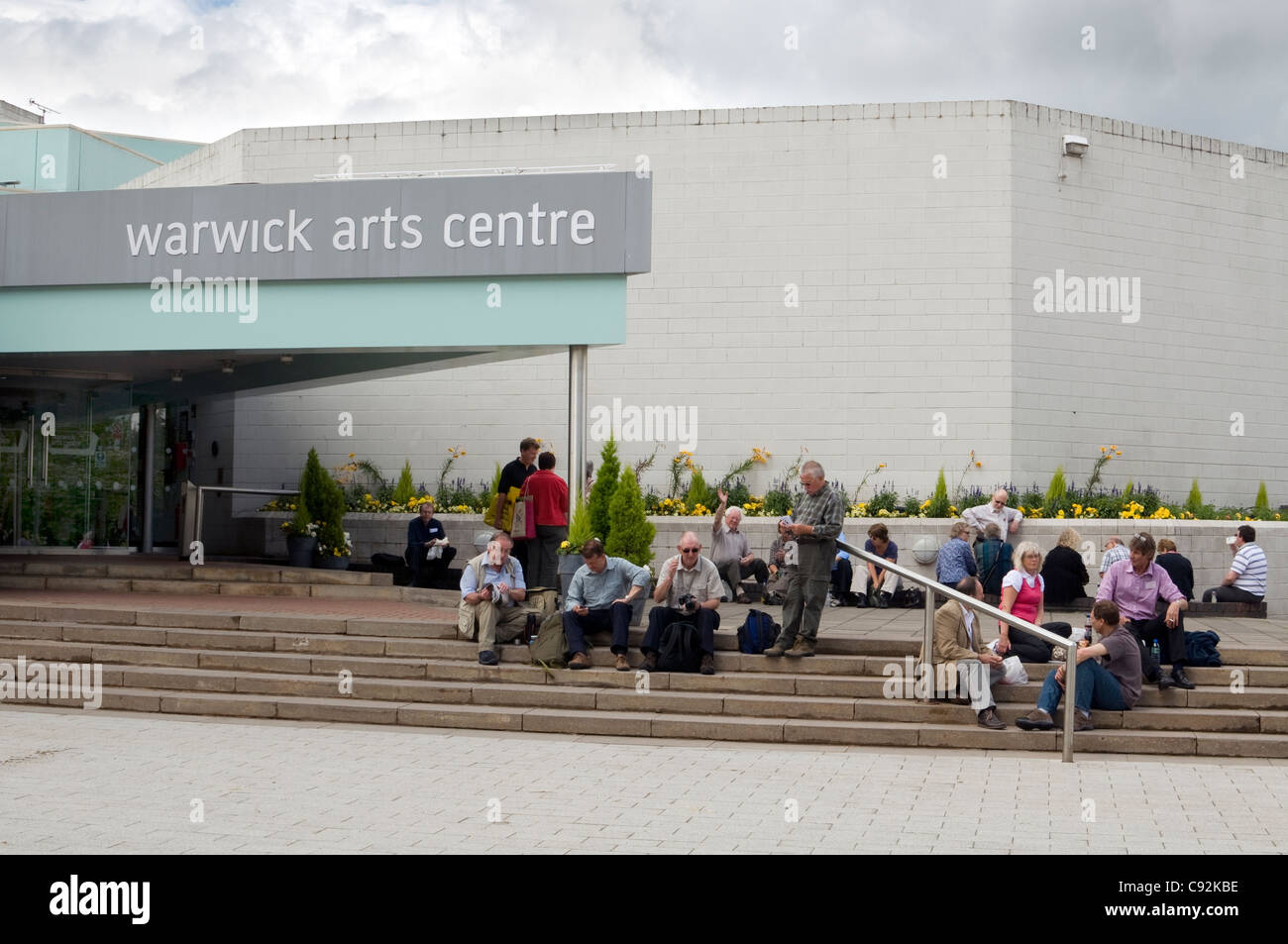Un groupe de gens assis sur les marches à l'entrée de l'Université de Warwick Arts Centre Banque D'Images