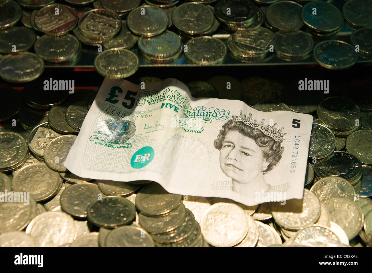 Focalisation étroite délibérée. UK de monnaie et Queen's head 5 lb bank note. Station de jeux électroniques Penny Falls machine de jeu Banque D'Images