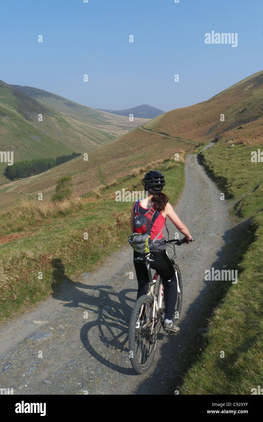 Une dame du vélo de montagne sur un chemin à commencer la traversée de Skiddaw dans le Lake District Banque D'Images