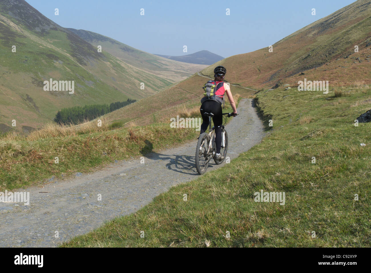 Une dame du vélo de montagne sur un chemin à commencer la traversée de Skiddaw dans le Lake District Banque D'Images