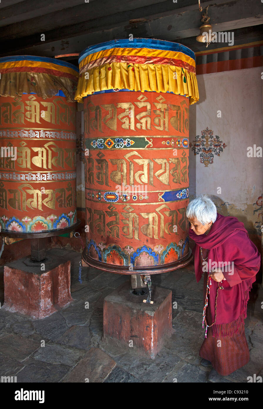 Une vieille femme, tourne une grande roue à l'Jampay Lhakhang à la périphérie de Jakar dans la vallée de Bumthang. Banque D'Images