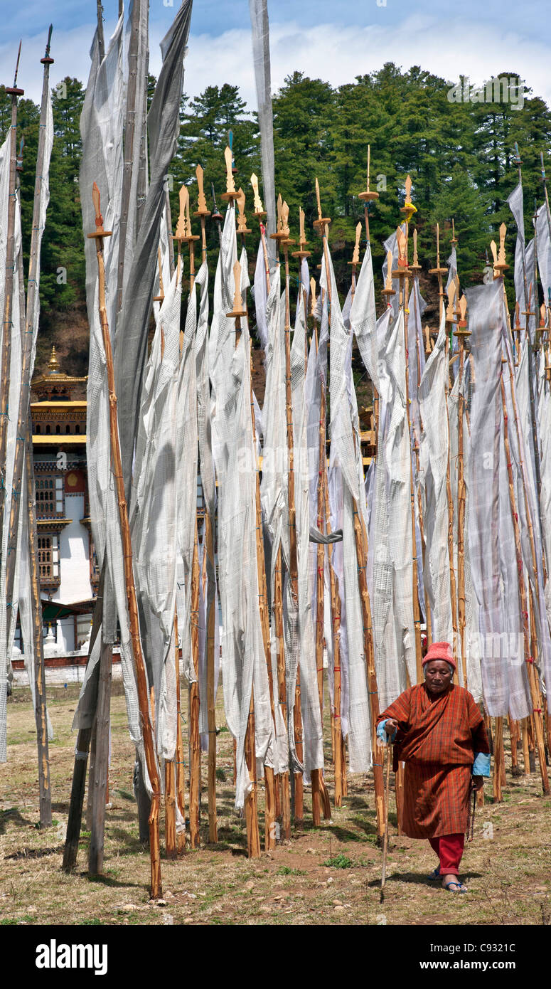 Un vieil homme passe devant de nombreux drapeaux de prière en dehors de Kurjey lungdhar Lhakhang. Banque D'Images Un vieil homme passe devant de nombreux drapeaux de prière en dehors de Kurjey lungdhar Lhakhang. Banque D'Images