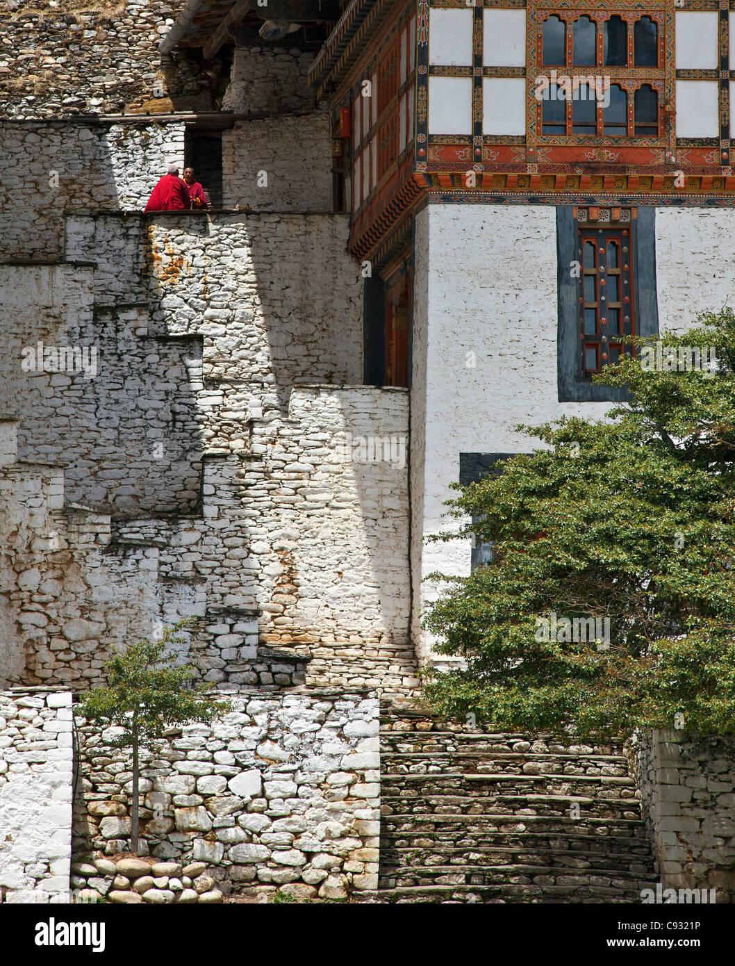Deux moines bouddhistes robe rouge chat au soleil sur les marches de pierre menant à la 17e siècle Kurjey Lhakhang temple. Banque D'Images