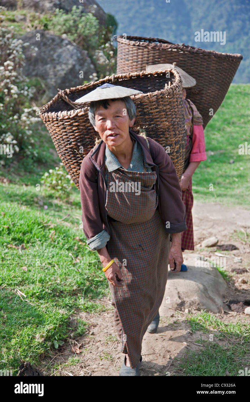 Les femmes avec des paniers en bambou grand rendez-vous pour recueillir les produits de leurs fermes à flanc de colline dans la vallée Mangde Chhu. Banque D'Images