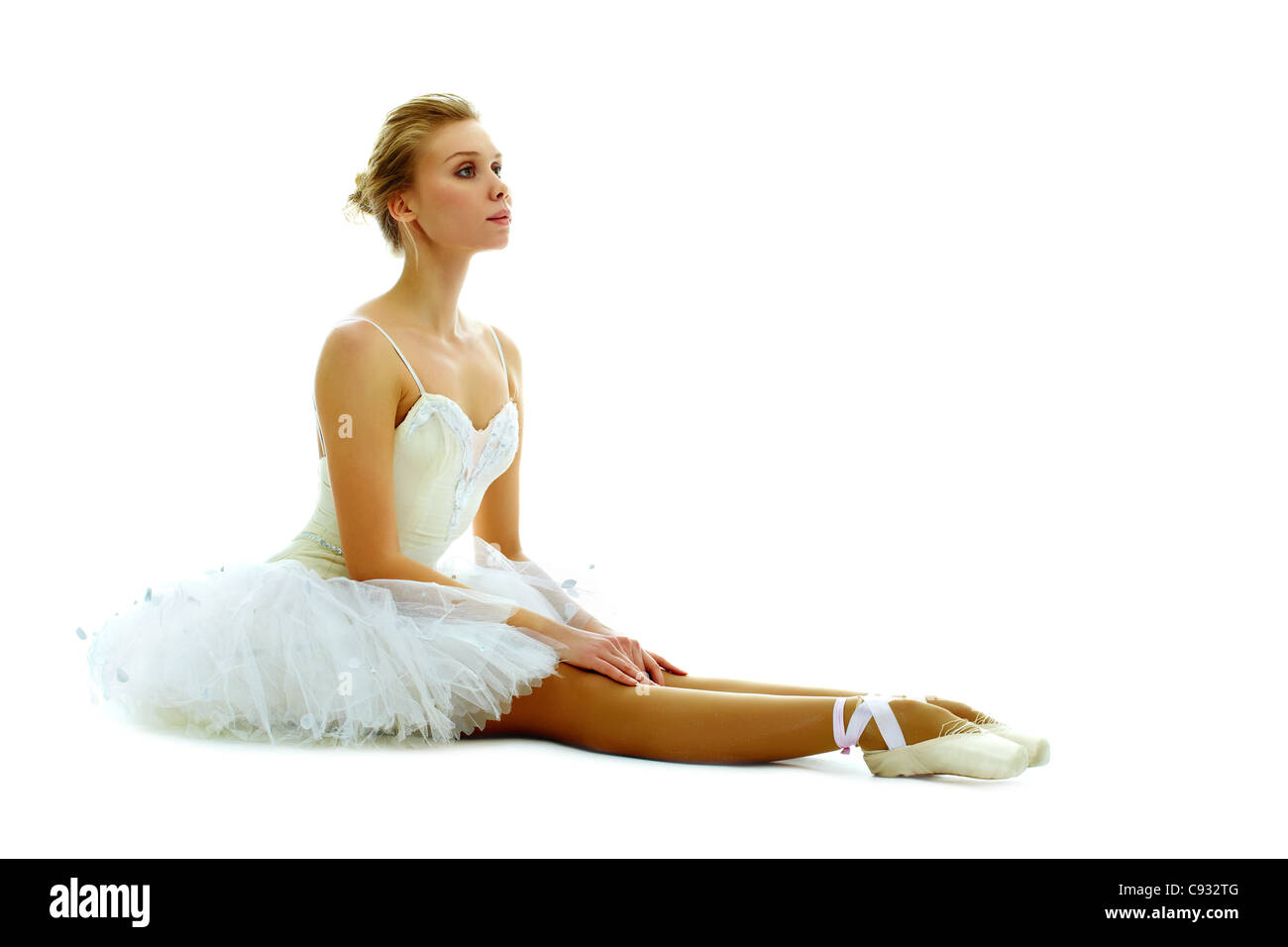 Portrait de ballerine gracieuse assis avec les jambes tendues sur fond blanc Banque D'Images