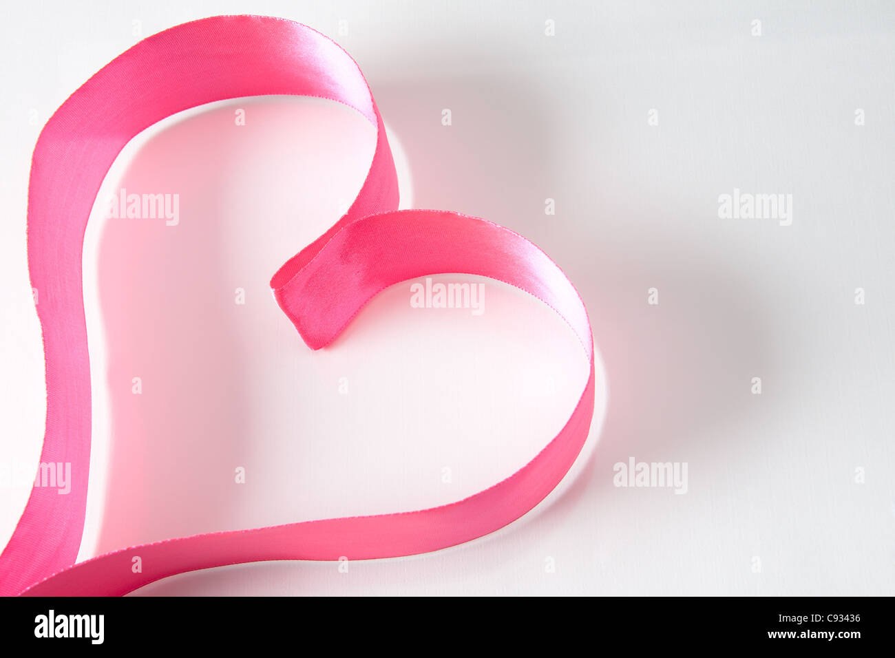 Forme de coeur composé de ruban rose sur fond blanc Banque D'Images