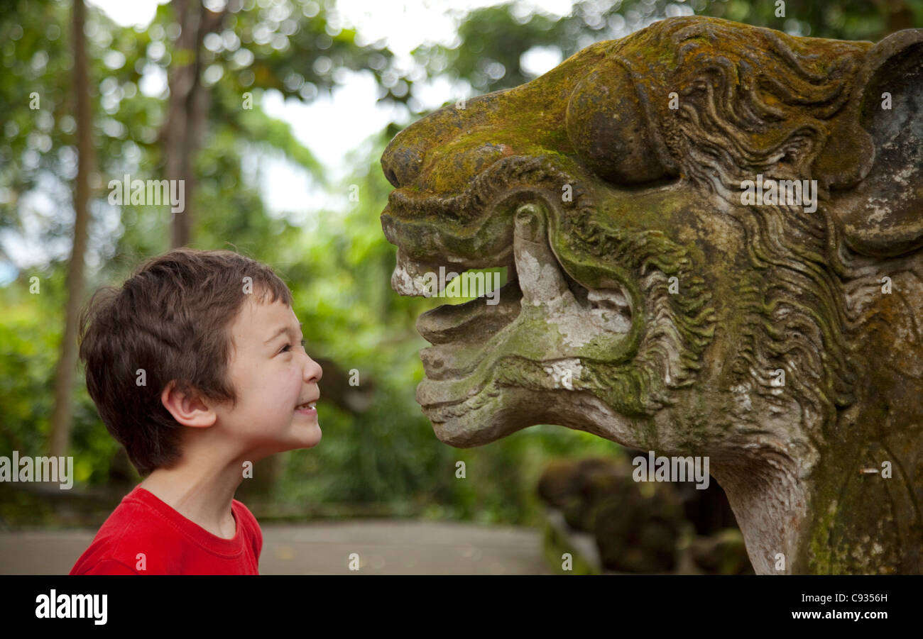 Bali, Ubud. Un jeune à une grogne touristiques également féroce de la sculpture sur pierre à Ubud's Sacred Monkey Forest. M. Banque D'Images