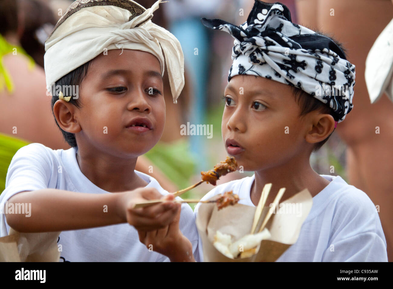 Bali, Ubud. Deux jeunes amis partager poulet satay au célébrations Nyepi à Ubud. Banque D'Images