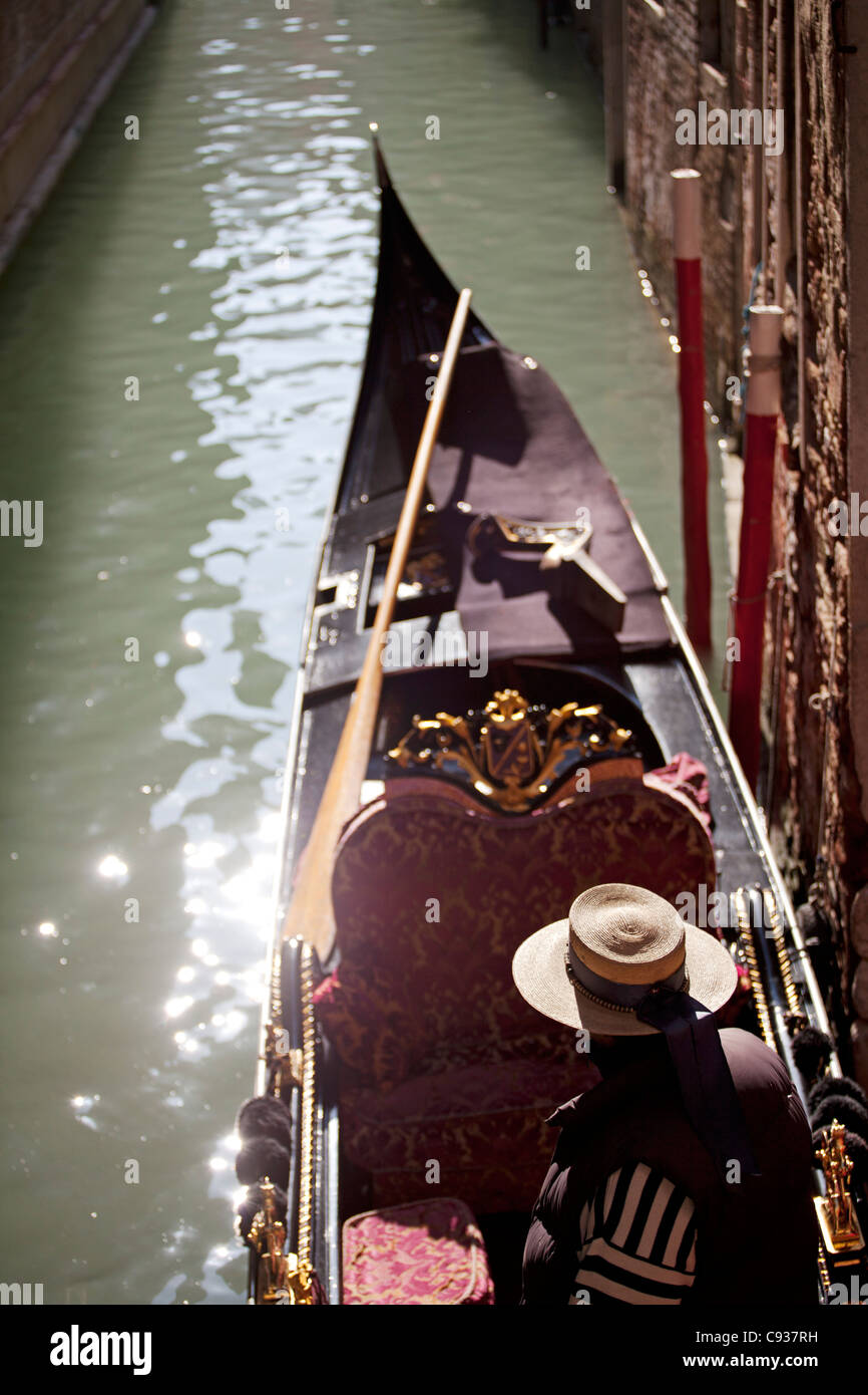 Venise, Vénétie, Italie ; un gondolier avec sa cabine dans l'un des nombreux canaux Banque D'Images