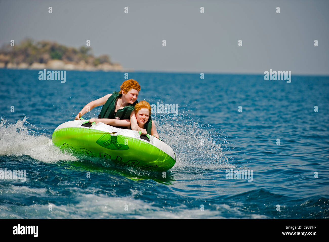 Au Malawi, le lac Malawi National Park. Deux jeunes garçons monter sur un anneau gonflable tiré par un hors-bord. M. Banque D'Images