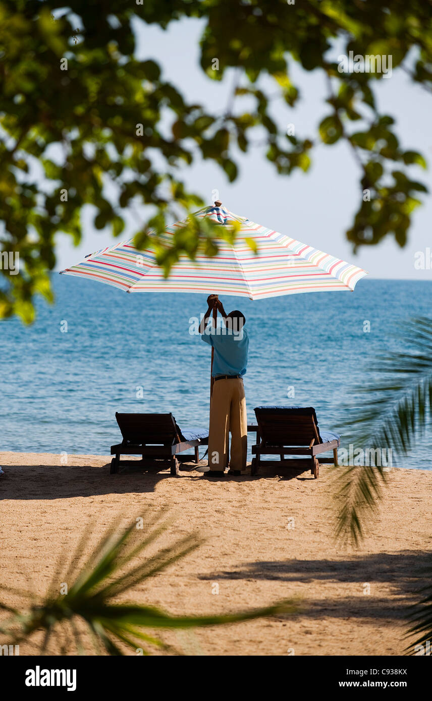 Au Malawi, le lac Malawi National Park. Un serveur à Pumulani Lodge met en place un pare-soleil. Banque D'Images