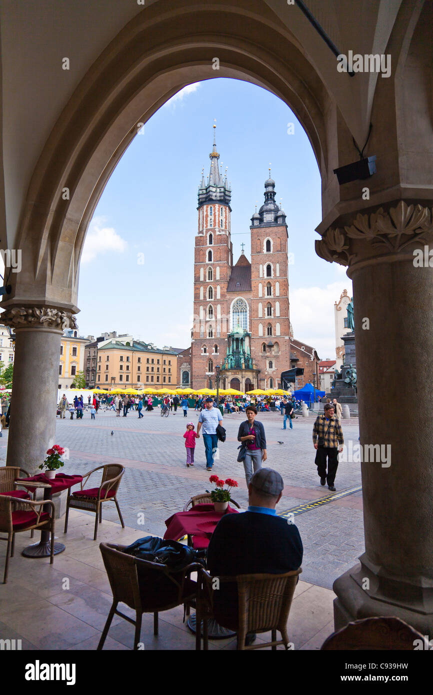 Pologne, Cracovie. Un café en plein air dans la région de Market Square avec une vue sur l'église de St Mary. Banque D'Images